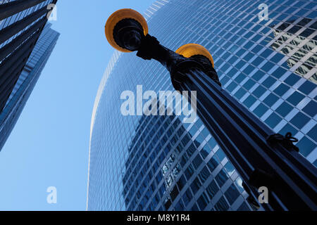 looking up at lamp post with blue sky and glass building reflections in background. Stock Photo