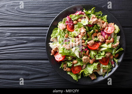 Healthy hearty salad of tuna, borlotti beans, tomatoes, lettuce close-up on a plate on the table. horizontal top view from above Stock Photo