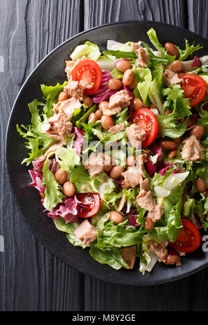 Healthy hearty salad of tuna, borlotti beans, tomatoes, lettuce close-up on a plate on the table. Vertical top view from above Stock Photo