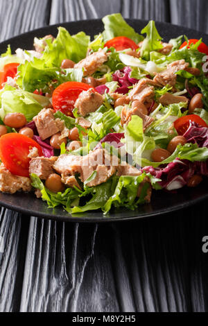 Healthy hearty salad of tuna, borlotti beans, tomatoes, lettuce close-up on a plate on the table. vertical Stock Photo