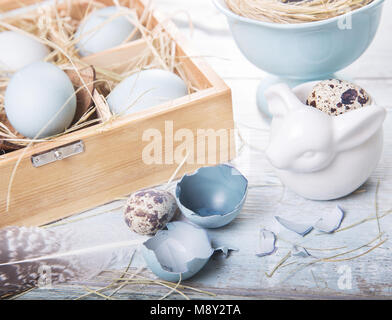 Easter decoration with dyed blue eggs and sawed eggs, feathers in a wooden box, festive background, postcard, rustic style. Top view Stock Photo