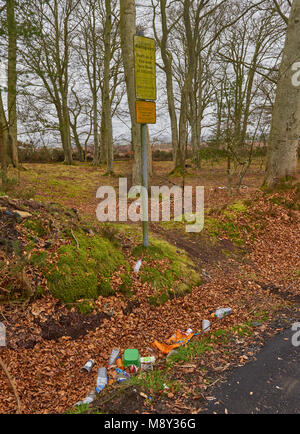 Beneath a sign stating that people will be fined for No Fly Tipping or Dumping, lies all sorts of debris from empty Cans and Bottles to Burger Boxes. Stock Photo