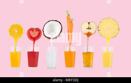 Fresh juice pours from fruits and vegetables in a glass on pastel pink background Stock Photo