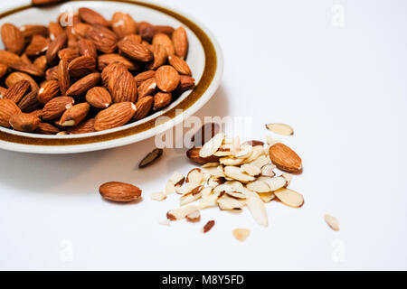 A small plate of almonds plain white background Stock Photo