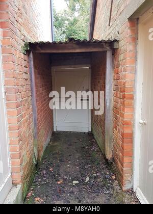 Outside doorway / gate with canopy between brick walls Stock Photo