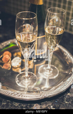 Two glasses of champagne or sparkling wine on a silver tray with the cork and bottle in the background Stock Photo