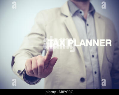 Businessman is pressing button on touch screen interface and selecting 'Tax planner'. Business concept. Stock Photo