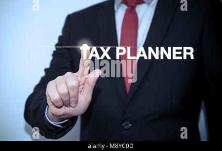 Businessman is pressing button on touch screen interface and selecting 'Tax planner'. Business concept. Stock Photo