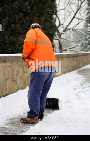 maintenance worker while he shovels snow from the sidewalk Stock Photo ...