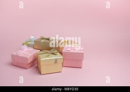 Close-up of color gift boxes with golden bows on pink background. Copy space Stock Photo