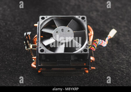 CPU heat sinker from a PC. Copper heatsinker with a fan for cooling the processor. Isolated on a dark background. Top view. Stock Photo