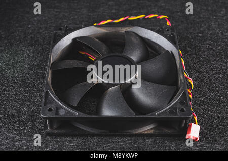 Black PC fan for cooling the case. Isolated on a dark background. Stock Photo