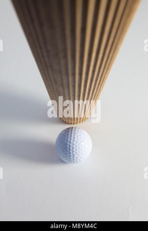 Corrugated brown paper roll and golf ball on the white desk. Exclamation mark. Stock Photo
