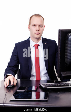 Business, people, documents and technology concept - a businessman looks straight, right-handed uses a computer mouse, a tablet on a desk, a computer  Stock Photo