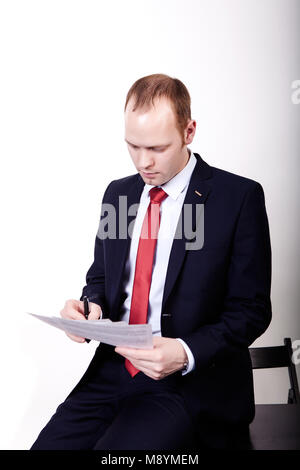 The auditor checks the important documentation, the man is holding the papers in his hands leaning against the table. Stock Photo
