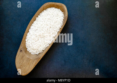 Rice in wooden dish which placed on dark blue background surface Stock Photo