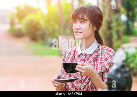 Asian beautiful women with hot drink in the morning with park garden background Stock Photo