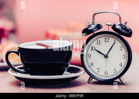 Black old clock with black coffee cup decoration on wooden table pink colortone Stock Photo