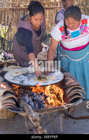 tortillas de maíz azul cociendose en comal de barro Stock Photo