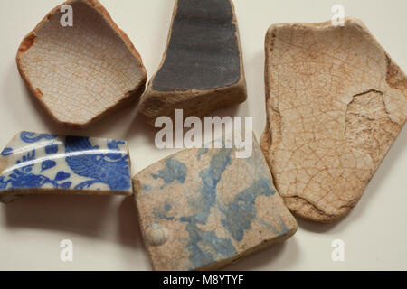 Broken pottery shards on a tabletop. Stock Photo