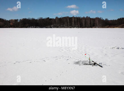 Fishing Rods fishing through bore hole on Frozen Lake at Bromma Sweden Stock Photo