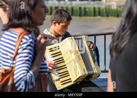 London, UK - July 09, 2017 - A young busker performing accordion on a crowd street at South Bank Stock Photo