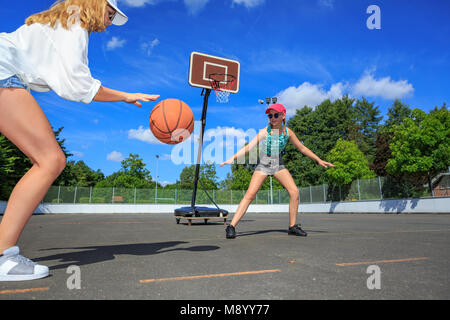 two teenage girls playing basketball in the park Stock Photo