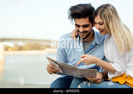 Happy tourist couple with map traveling outdoors Stock Photo