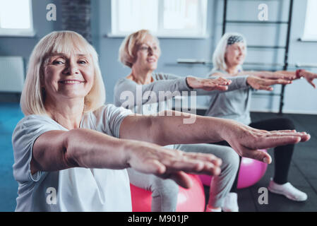 Cheerful elderly women stretching hands at fitness club Stock Photo