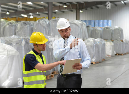 managers and workers in the logistics industry talk about working with chemicals in the warehouse Stock Photo
