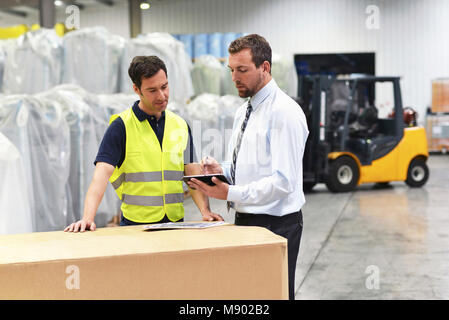 meeting of the manager and worker in the warehouse - forklift and interior of the industrial building Stock Photo