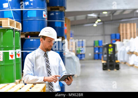 manager in a logistic company work in a warehouse with chemicals - checking goods with tablet Stock Photo