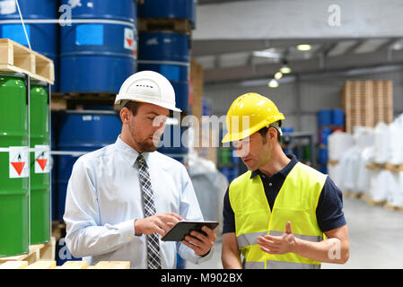 managers and workers in the logistics industry talk about working with chemicals in the warehouse Stock Photo