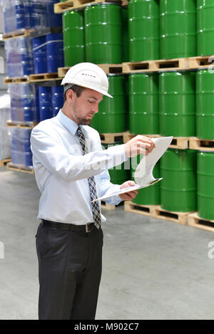 manager in a logistic company work in a warehouse with chemicals - checking goods with clipboard Stock Photo