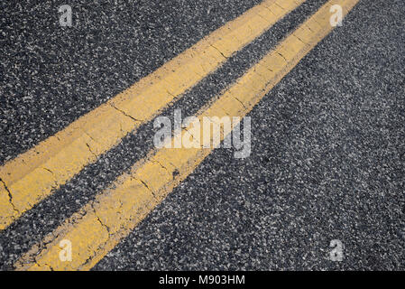 double yellow street lines on old country asphalt road. Close up. Stock Photo