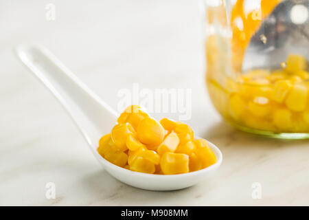 Corn seeds in ceramic spoon on kitchen table. Stock Photo
