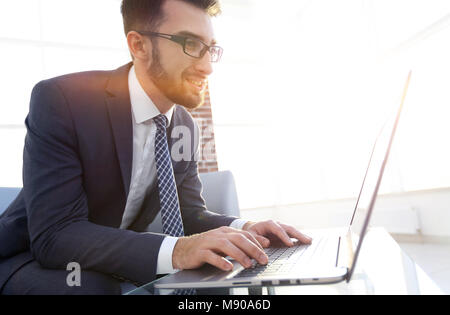Portrait of young serious businessman working with laptop and document Stock Photo