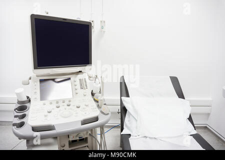 Black bed and white pillow next to ultrasound in white hospital room Stock Photo