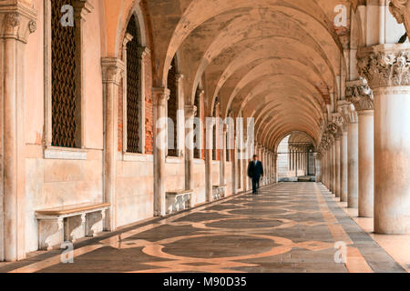 Colonnade of Doge's Palace in Venice with man in suit approaching beneath cloister arches Stock Photo