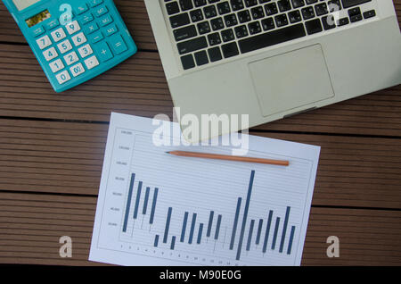 business graph laptop and calculator on wooden floor Stock Photo