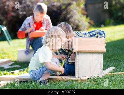 Kids brothers making birdhouse together on lawn in summertime Stock Photo