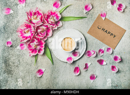 Cup of coffee surrounded with pink tulip flowers, marble background Stock Photo