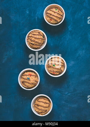 Safe-to-eat raw monster cookie dough in small portion bowl on blue background. Ideas and recipes for kids and toddlers meal. Top view or flat-lay. Copy space for text. Stock Photo