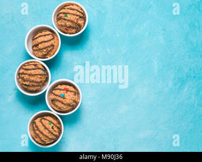 Safe-to-eat raw monster cookie dough in small portion bowl on blue background. Ideas and recipes for kids and toddlers meal. Top view or flat-lay. Copy space for text. Stock Photo