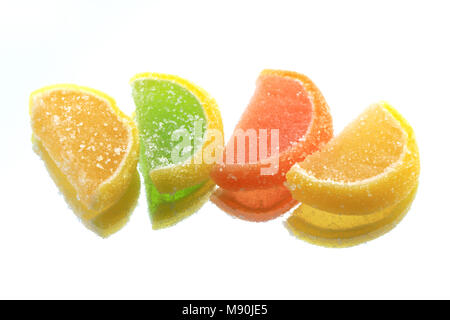 Few colored fruit jelly lying in a row on glass background with reverberation Stock Photo