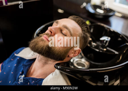 Portrait of young man in barber shop waiting for washing hair Stock Photo