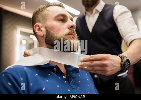 Cropped portrait of barber putting hairdresser tape around customer neck Stock Photo