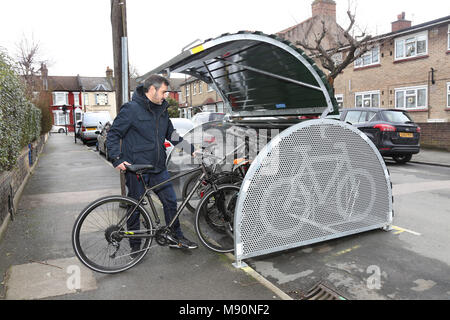 A cyclist places his bike into a secure on-street bicycle store recently installed on a residential London street. Stock Photo