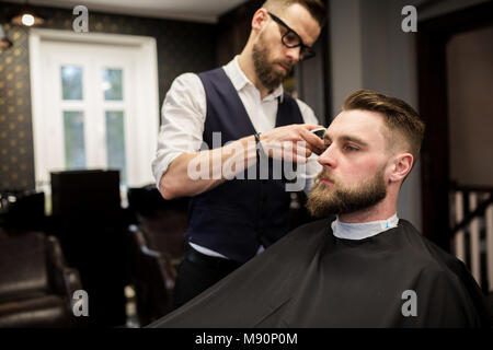 Profile portrait of young man having haircut in hair salon Stock Photo