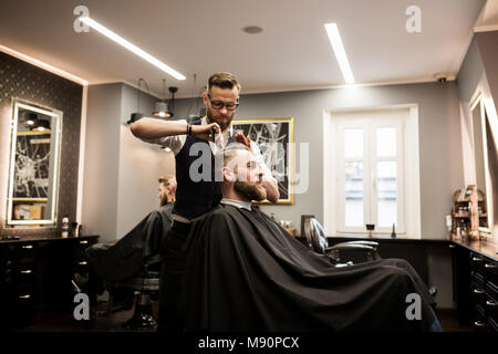 Profile portrait of smiling man having hair cut in salon Stock Photo
